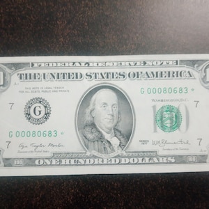 May include: A crisp, new $100 United States Federal Reserve Note. The bill features a portrait of Benjamin Franklin and the text "The United States of America." The serial number is G00080683.