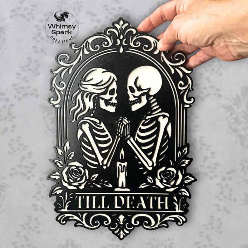 May include: Black and white wall decor featuring two skeletons holding hands, with a candle between them. The phrase "TILL DEATH" is displayed at the bottom. The design is framed with decorative flourishes and roses.