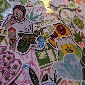 May include: A collection of colorful stickers with cannabis-related designs. The stickers feature illustrations of marijuana leaves, smoking figures, and text like "Smoke Everyday" and "More Weed". The stickers are in various shapes and sizes.