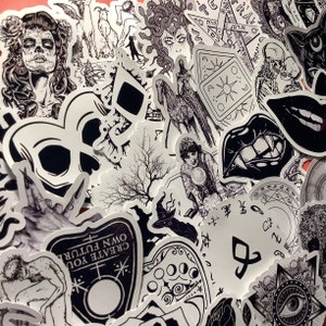 Puede incluir: Una colecci&oacute;n de pegatinas en blanco y negro con varias ilustraciones g&oacute;ticas y ocultas. Los dise&ntilde;os incluyen calaveras, Medusa, cartas del tarot, una bruja, una tabla Ouija y otros s&iacute;mbolos m&iacute;sticos. Las pegatinas est&aacute;n dispuestas sobre un fondo rosa.