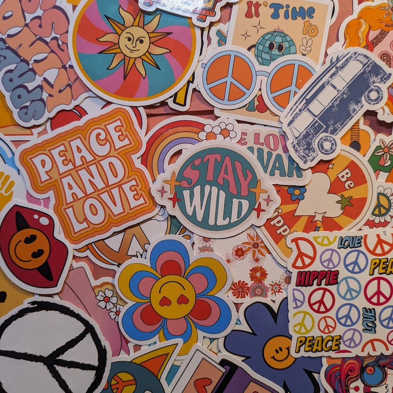 May include: A collection of colorful, retro-style stickers with various designs. The stickers feature phrases like "Peace and Love" and "Stay Wild," along with images of a smiling sun, flowers, peace signs, and a vintage van. The color palette includes orange, blue, pink, and yellow.