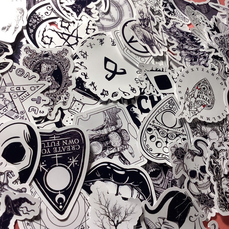 Puede incluir: Una colecci&oacute;n de pegatinas en blanco y negro con temas ocultos y g&oacute;ticos. Los dise&ntilde;os incluyen calaveras, tableros Ouija, lunas y texto que dice "CREATE YOUR OWN FUTURE". Las pegatinas son de varias formas y tama&ntilde;os.