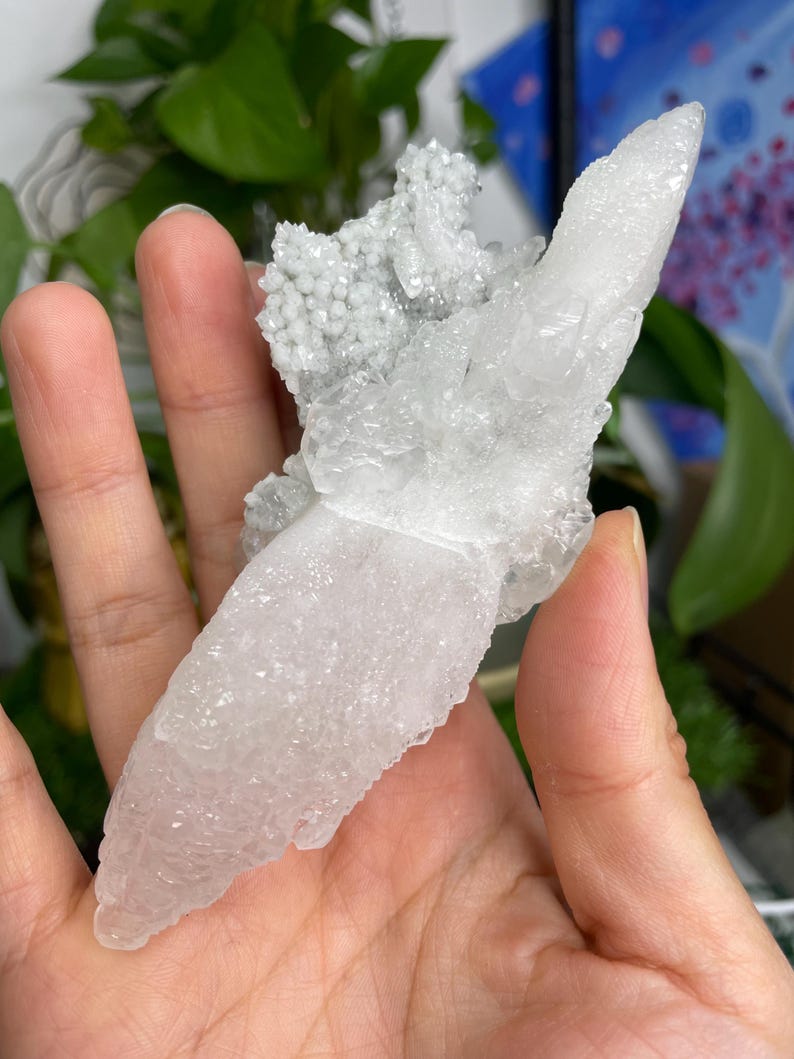 Op de afbeelding: Een witte kristalkluster met een unieke, puntige vorm. De kristal heeft een doorschijnende, melkachtig witte uitstraling en is een prachtig voorbeeld van natuurlijke schoonheid.