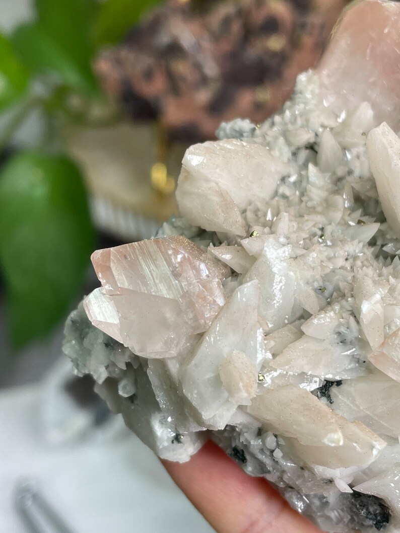 May include: A cluster of white and pink crystals with a shimmery, iridescent finish. The crystals are arranged in a natural, organic pattern, creating a unique and beautiful display.