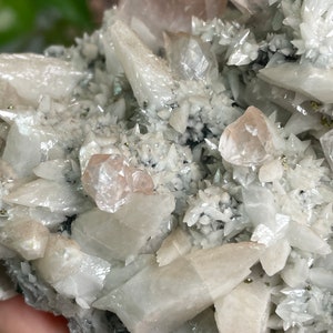 May include: A cluster of white and pink crystals with a sparkly, iridescent finish. The crystals are arranged in a random, organic pattern, creating a visually interesting and unique piece.