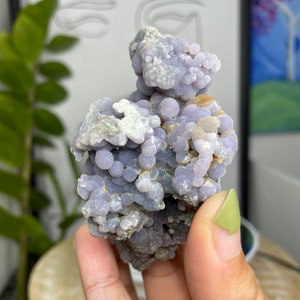 Puede incluir: Un racimo de ágata púrpura y blanca con una textura burbujeante. La ágata es una piedra natural con una apariencia única e interesante.