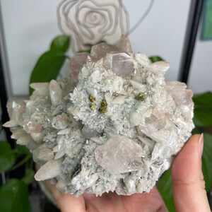 May include: A cluster of white and pink crystals with small gold flecks. The crystals are arranged in a cluster and have a rough, natural texture.