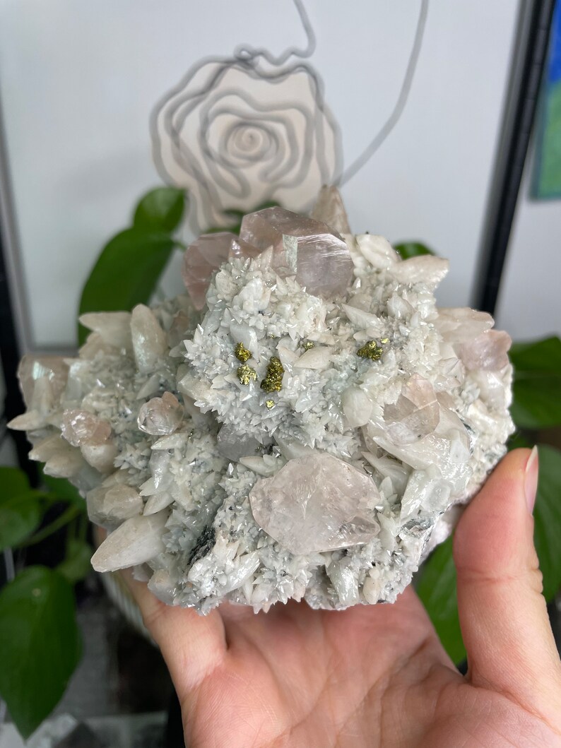 May include: A cluster of white and pink crystals with small gold flecks. The crystals are arranged in a cluster and have a rough, natural texture.