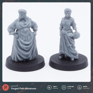 Könnte beinhalten: Zwei 3D-gedruckte Miniaturfiguren von Frauen in langen Kleidern und Kopfbedeckungen. Die Figur links steht auf einem schwarzen Sockel und die Figur rechts auf einem grauen Sockel.