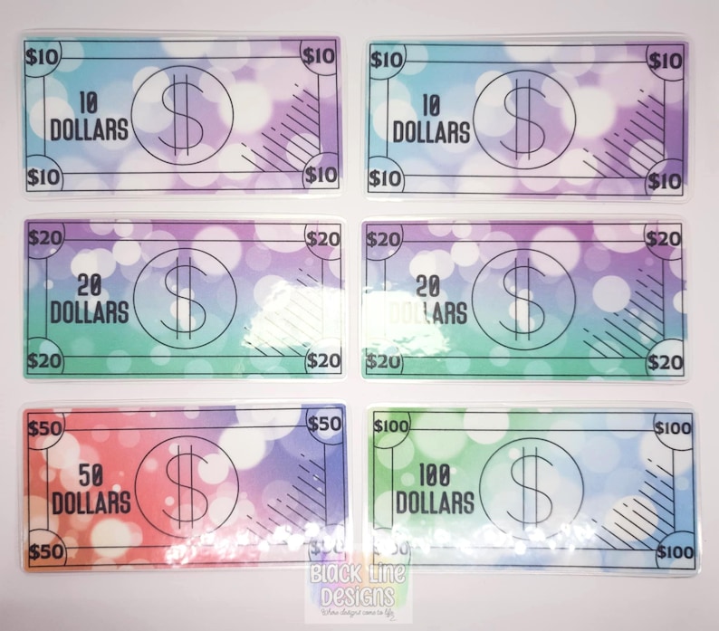 May include: Six colorful play money bills with different denominations: $10, $20, $50, and $100. Each bill has a dollar sign and the amount written out.