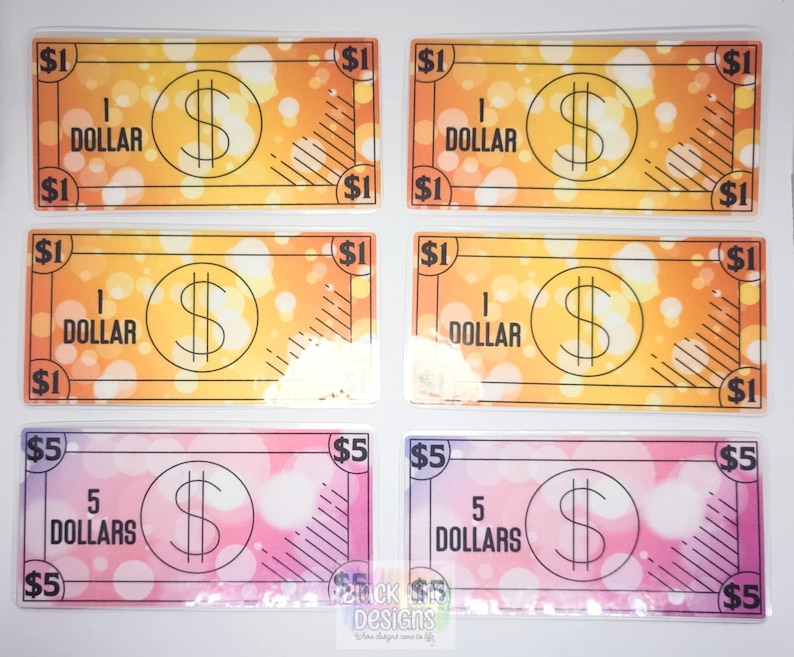 May include: Six play money bills, four are yellow with a $1 bill design and the text "1 DOLLAR" and two are pink with a $5 bill design and the text "5 DOLLARS".