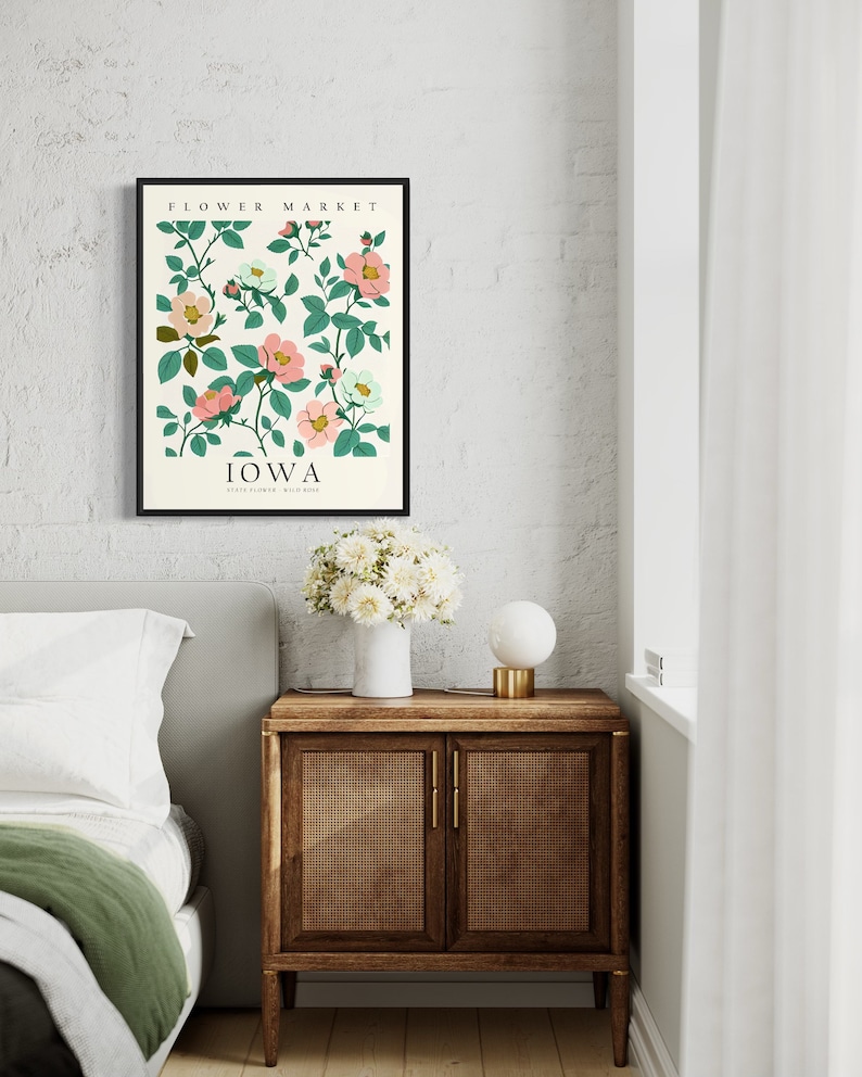 May include: A framed print with a floral design featuring pink and white flowers with green leaves. The print has the text "FLOWER MARKET" and "IOWA STATE FLOWER WILD ROSE" in black text.