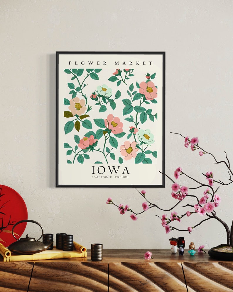 May include: A framed print featuring a botanical illustration of pink and white wild roses, with the text "FLOWER MARKET" at the top and "IOWA STATE FLOWER - WILD ROSE" at the bottom.