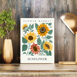 May include: A white poster with the text "FLOWER MARKET" and "SUNFLOWER" in black. The poster features a colorful illustration of sunflowers with green leaves on a white background.