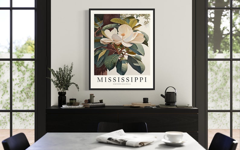 Może przedstawiać: Wizerunek vintage botaniczny przedstawiający biały kwiat magnolii z zielonymi liśćmi. Plakat ma czarną ramę i tekst "MISSISSIPPI SOUTHERN MAGNOLIA" na dole.