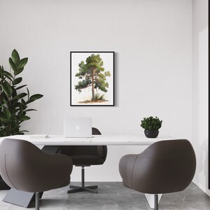 May include: A black framed print of a watercolor painting of a green pine tree on a white background. The print is hanging on a white wall in a modern office setting with a white desk, two brown leather chairs, a laptop, and a small potted plant.