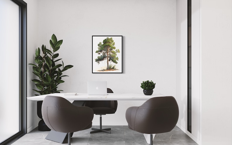 May include: A black framed print of a watercolor painting of a green pine tree on a white background. The print is hanging on a white wall in a modern office setting with a white desk, two brown leather chairs, a laptop, and a small potted plant.