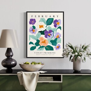 Puede incluir: Una impresi&oacute;n enmarcada con un dise&ntilde;o floral que presenta flores moradas, blancas y naranjas con hojas verdes. La impresi&oacute;n tiene el texto "FEBRUARY" y "VIOLET PRIMROSE" con las palabras "MODESTY, PATRIOTISM, YOUNG LOVE" debajo.