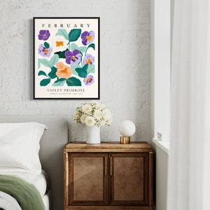 Puede incluir: Una impresi&oacute;n enmarcada con una ilustraci&oacute;n floral de flores moradas, blancas y naranjas con hojas verdes. El texto "FEBRERO" y "PRIMULA VIOLETA" est&aacute; impreso debajo de la ilustraci&oacute;n.