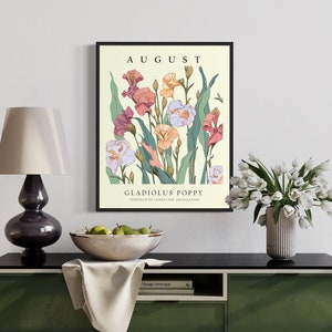 May include: A framed botanical illustration of a bouquet of pink, white, and orange gladiolus and poppy flowers with green leaves on a cream background. The text "AUGUST" is at the top of the image and "GLADIOLUS POPPY" is at the bottom of the image.