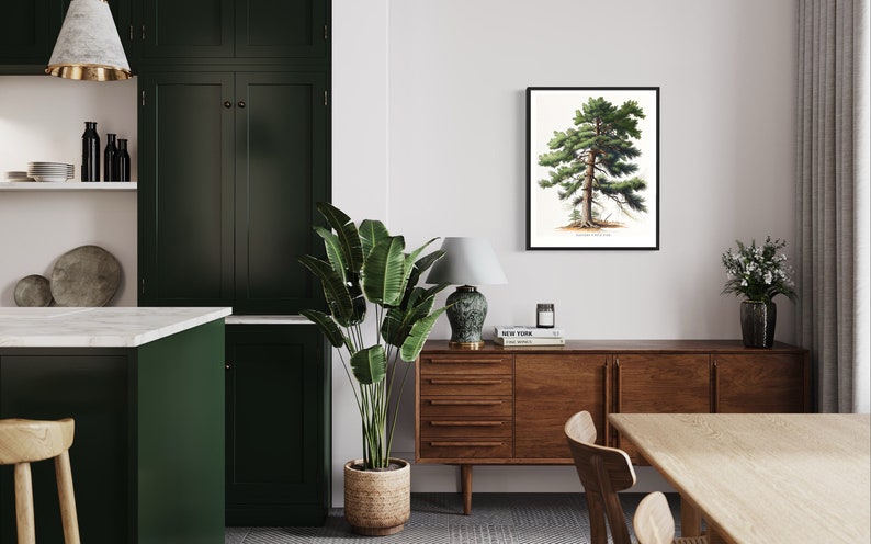 May include: A framed botanical illustration of a pine tree hangs on a white wall above a wooden dresser with a lamp and books. A large green plant is in a woven basket on the floor. The room has a modern farmhouse style.
