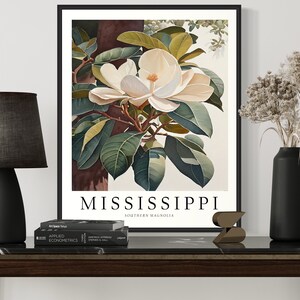 Może przedstawiać: Ilustracja botaniczna w ramie przedstawiająca biały kwiat magnolii południowej z zielonymi liśćmi. Druk zawiera tekst "MISSISSIPPI SOUTHERN MAGNOLIA" na dole.