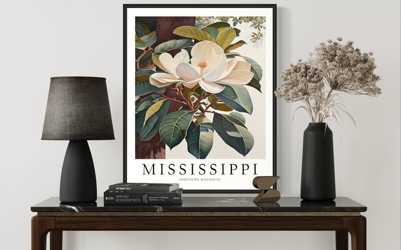 Może przedstawiać: Ilustracja botaniczna w ramie przedstawiająca biały kwiat magnolii południowej z zielonymi liśćmi. Druk zawiera tekst "MISSISSIPPI SOUTHERN MAGNOLIA" na dole.