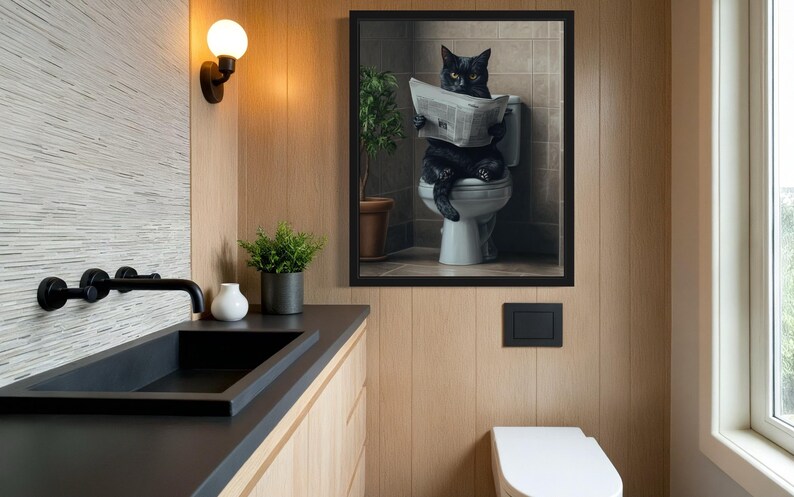 May include: A black cat sitting on a toilet reading a newspaper in a framed picture. The picture is hanging on a wood panel wall in a bathroom.