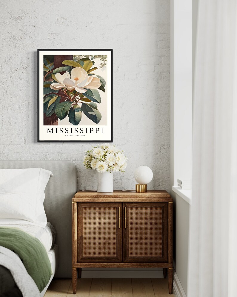 Może przedstawiać: Ilustracja botaniczna w ramie przedstawiająca biały kwiat magnolii z zielonymi liśćmi. Pod obrazem znajduje się napis "MISSISSIPPI SOUTHERN MAGNOLIA".