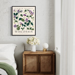 May include: A framed botanical print featuring purple flowers with green leaves on a cream background. The print has the text "FLOWER MARKET WISCONSIN STATE FLOWER WOOD SORREL" at the top and bottom.