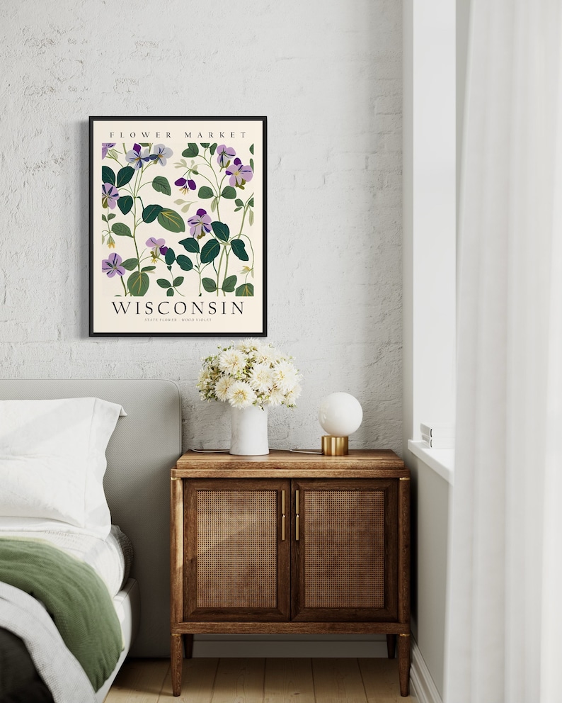 May include: A framed botanical print featuring purple flowers with green leaves on a cream background. The print has the text "FLOWER MARKET WISCONSIN STATE FLOWER WOOD SORREL" at the top and bottom.