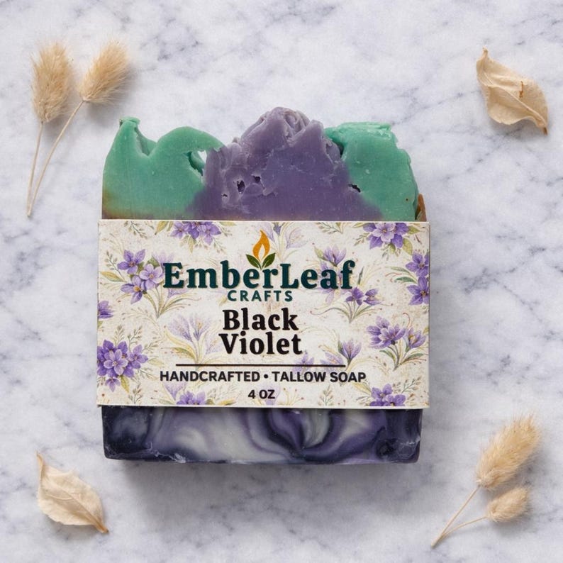 Tallow bar soap bundle by EmberLeaf Crafts. The image shows a variety of colorful, natural soaps—Rose Flower, Citrus Grove, and Oak & Elderberry—neatly laid out on a clean marble surface with scattered white flower petals.