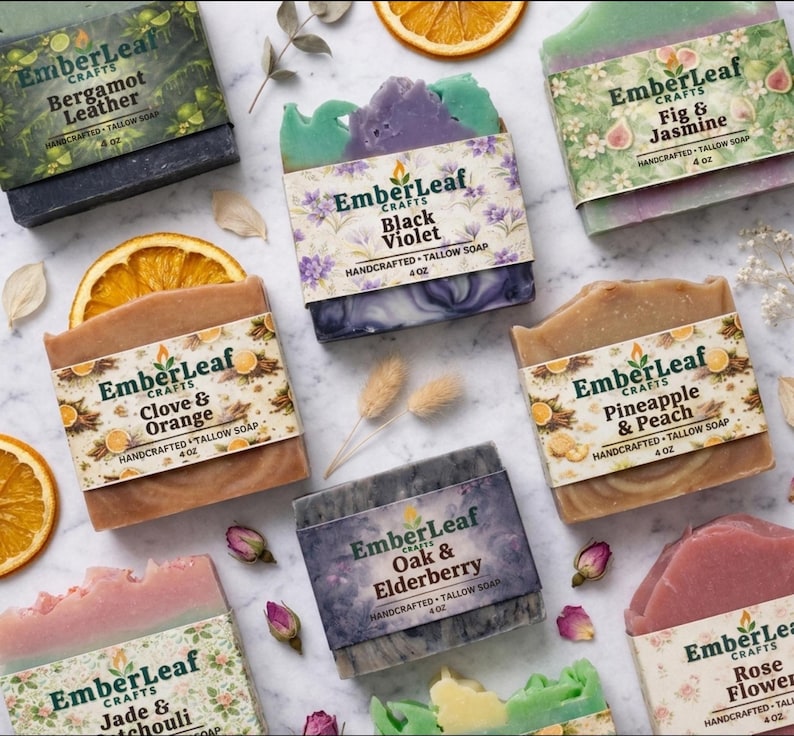 Tallow bar soap bundle by EmberLeaf Crafts. The image shows a variety of colorful, natural soaps—Rose Flower, Citrus Grove, and Oak & Elderberry—neatly laid out on a clean marble surface with scattered white flower petals.