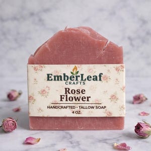 Tallow bar soap bundle by EmberLeaf Crafts. The image shows a variety of colorful, natural soaps—Rose Flower, Citrus Grove, and Oak & Elderberry—neatly laid out on a clean marble surface with scattered white flower petals.