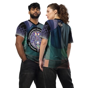 May include: Two people wearing short-sleeved shirts with a colorful abstract design. The shirt on the left has a black circle with the text "Cryptozoological Society" and "Filia Monstra" in white. The shirt on the right has a black circle with the text "DISCO" in white.