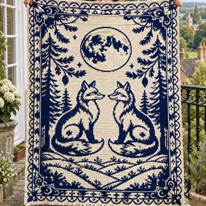 May include: A rectangular crochet blanket featuring a cream-colored background with a dark navy blue pattern. The design depicts two foxes facing each other, surrounded by pine trees, a full moon, and a decorative border of geometric shapes.