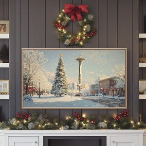 May include: A snowy winter scene with a Christmas tree and the Space Needle in Seattle, Washington. The scene is framed by a gold picture frame and a Christmas wreath with red berries and lights.