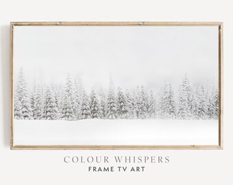 Könnte beinhalten: Ein Schwarzweißfoto eines schneebedeckten Waldes mit leichtem Nebel. Das Bild ist in einem hellen Holzrahmen gerahmt. Der Text "COLOUR WHISPERS FRAME TV ART" ist unter dem Rahmen gedruckt.