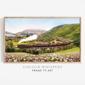 May include: A red train travels over a stone bridge in a green valley. The train is surrounded by lush green hills and a blue lake. The foreground is filled with white and purple wildflowers.