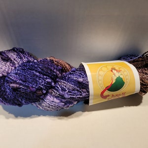 May include: A skein of purple, white, and brown yarn with a label that reads "Lady Bug Yarn".