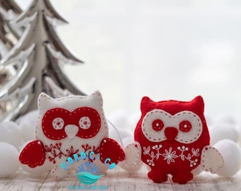 May include: Two felt owl ornaments with white bodies and red wings. The owls have white eyes and red beaks. The owls are decorated with white embroidery.