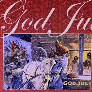 May include: A red card featuring the text God Jul in white script. The central illustration depicts a white goat, a figure with a long white beard and red hat, and a small child in a red hat, all set against a snowy cabin scene with a window.