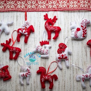 May include: Twelve felt Christmas ornaments in red and white with Scandinavian folk art designs. The ornaments are shaped like reindeer, horses, and squirrels.