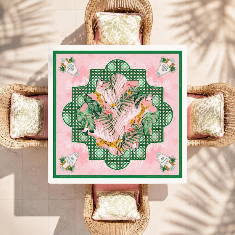 May include: A square tablecloth featuring a pink background with a central green lattice frame. The design includes tropical palm leaves, pink flamingos, and yellow leopards. Four corner motifs display a bottle graphic with the text 'Chandon'.