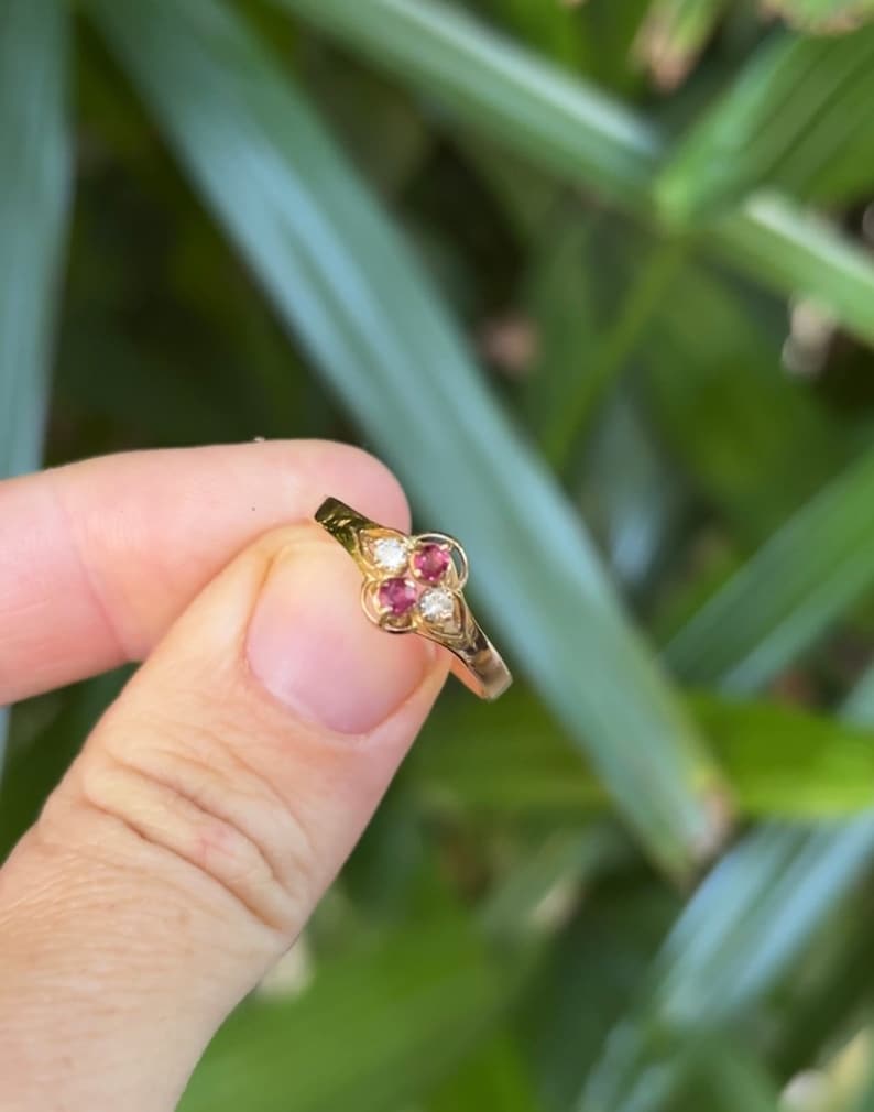 May include: A gold ring with three red gemstones and a single white gemstone set in a clover design.
