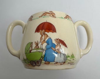 Taza Royal Doulton Bunnykins de dos asas "Abraza una taza" - Diseño de Barbara Vernon, década de 1930