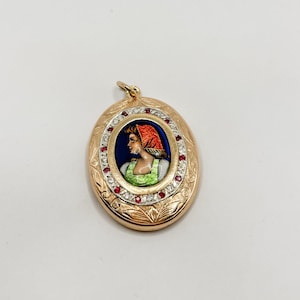 May include: Gold oval locket pendant with a painted portrait of a woman wearing a red headscarf. The locket is decorated with a border of diamonds and rubies.