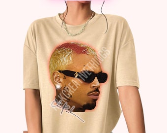 May include: A beige t-shirt with a graphic print of a man's face wearing sunglasses. The man has blonde and red hair and a beard. The text "DIGITAL DOWNLOAD" is in pink letters at the top of the image.