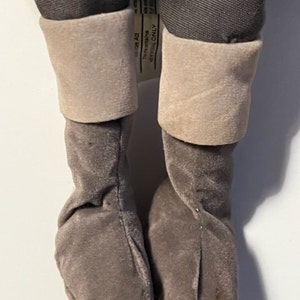 May include: A pair of gray plush boots with a white cuff. The boots are made of a soft, fuzzy material and have a simple design.