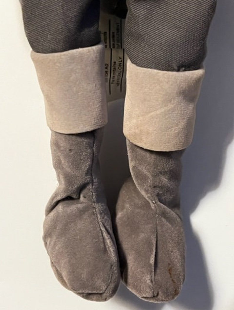 May include: A pair of gray plush boots with a white cuff. The boots are made of a soft, fuzzy material and have a simple design.